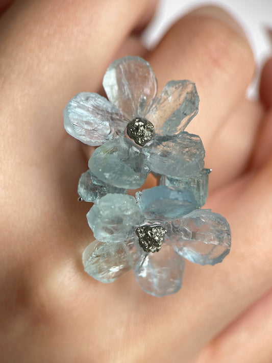 Close-up hand shot of aquamarine and chalcopyrite double bloom ring with raw and hand-cut crystal details