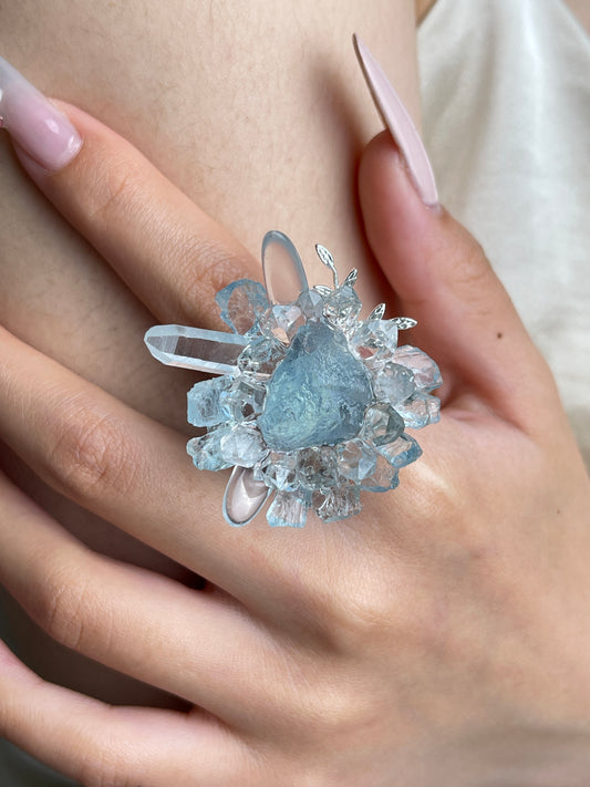 Close up of raw aquamarine Herkimer Diamond Quartz and clear quartz flower ring worn on hand