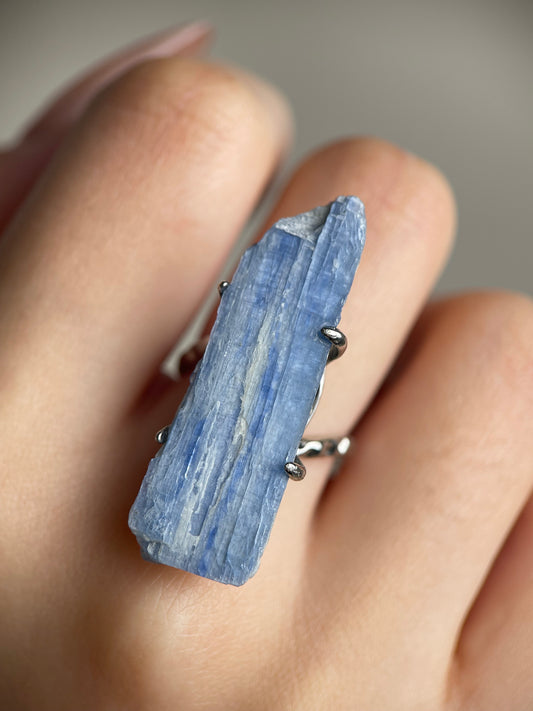 Close-up hand shot of blue kyanite mineral specimen ring showing natural blade-like crystal texture
