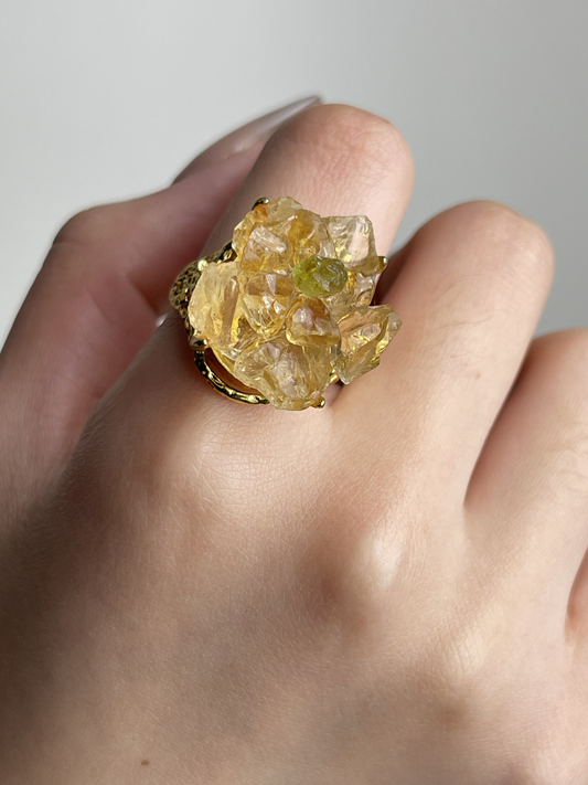 Citrine and Peridot crystal blossom ring worn on hand, featuring raw golden citrine petals with a natural green peridot center in a floral design.