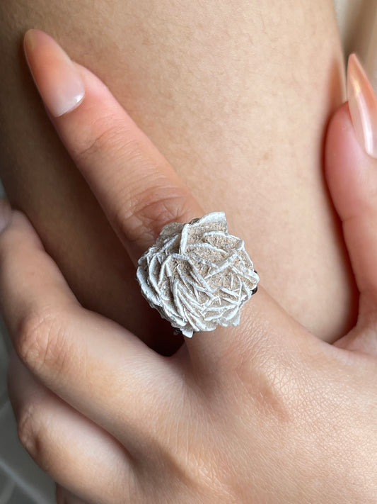 Close-up hand shot of Desert Rose mineral specimen ring from Morocco showing layered natural crystal texture.