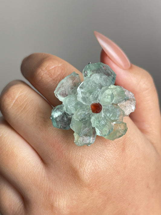 Close-up of green quartz flower ring with garnet center on hand