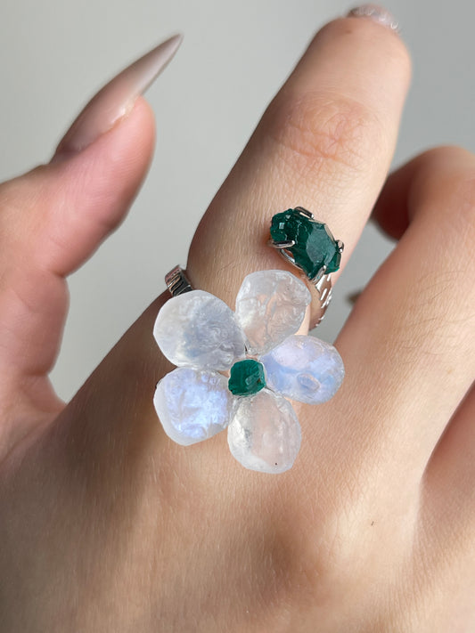 Close-up of Moonstone and Dioptase crystal flower ring worn on hand
