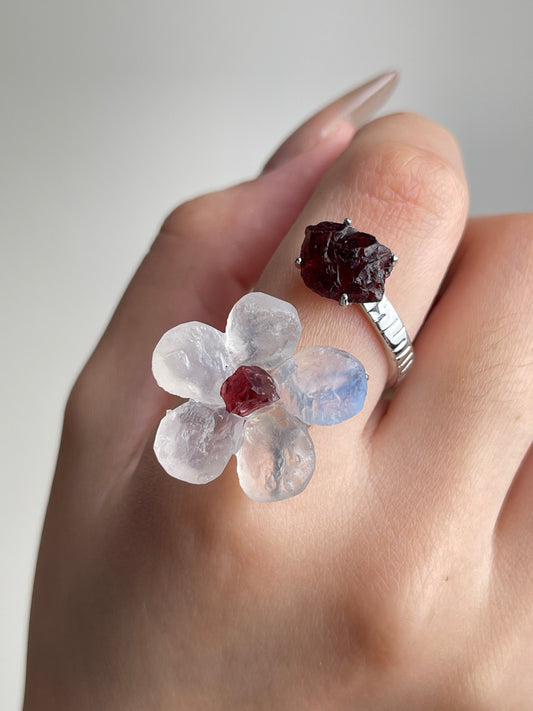 Close-up of Moonstone and Garnet crystal flower ring worn on hand