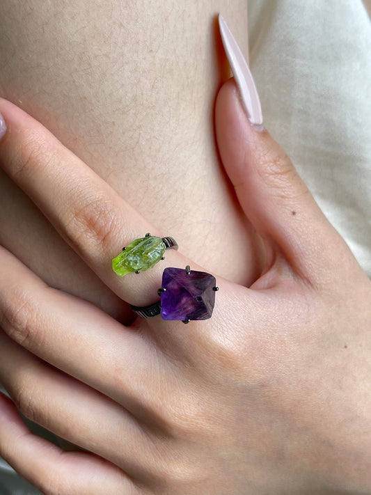 Close up of raw peridot and purple fluorite ring worn on hand