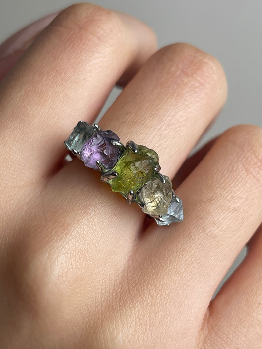 Close-up of rainbow raw crystal ring with aquamarine citrine peridot amethyst and blue apatite worn on hand