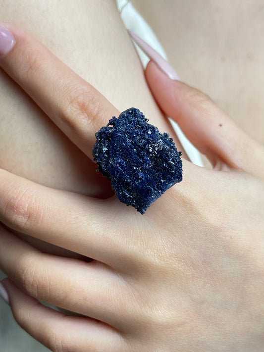 Close-up hand view of a raw Blue Sapphire mineral specimen ring.