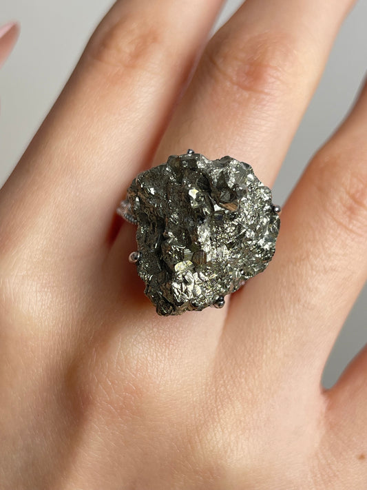 Close up of raw chalcopyrite mineral specimen ring worn on hand