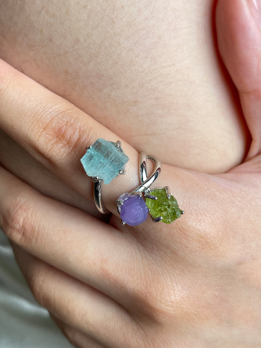 Close up of raw peridot, purple grape agate and raw aquamarine ring worn on hand