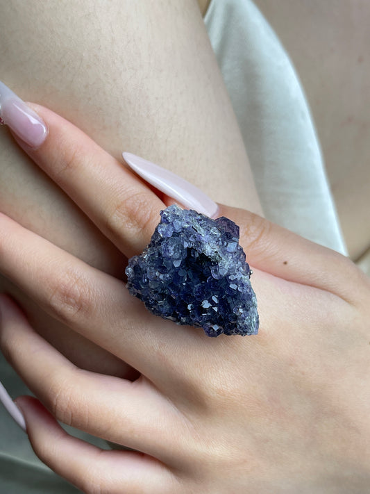Close-up of Tanzanite-colored Fluorite mineral specimen ring worn on hand