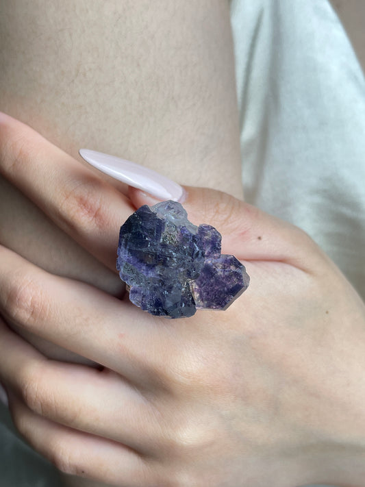 Close-up hand wearing raw Tanzanite Fluorite crystal ring