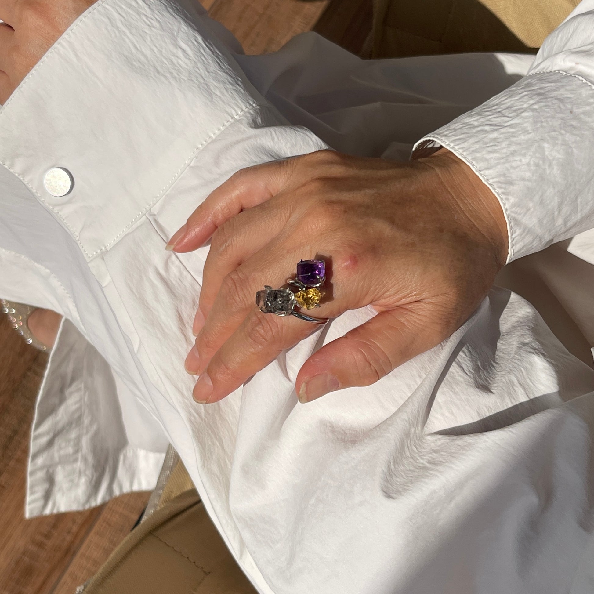 Close up of amethyst, citrine and black tourmalinated quartz freeform ring worn on hand