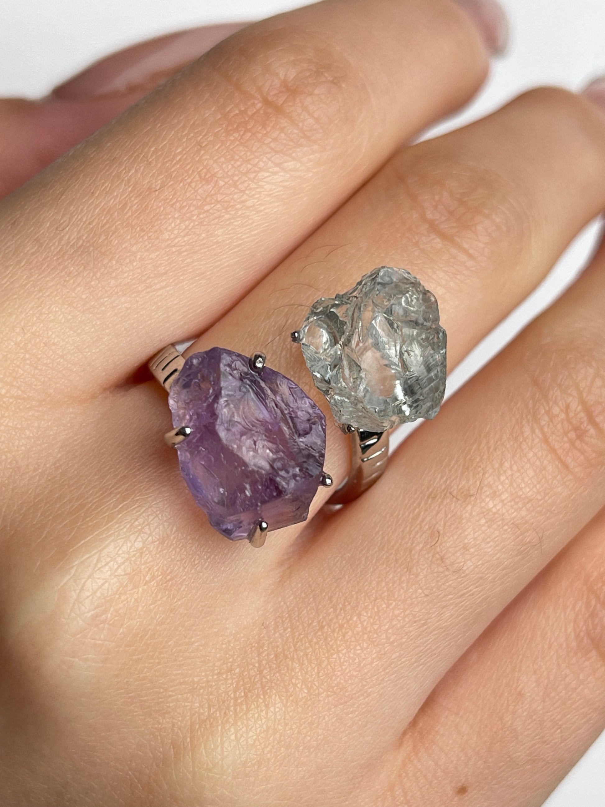 Close up of amethyst and green quartz raw crystal twin ring worn on hand natural unpolished crystals