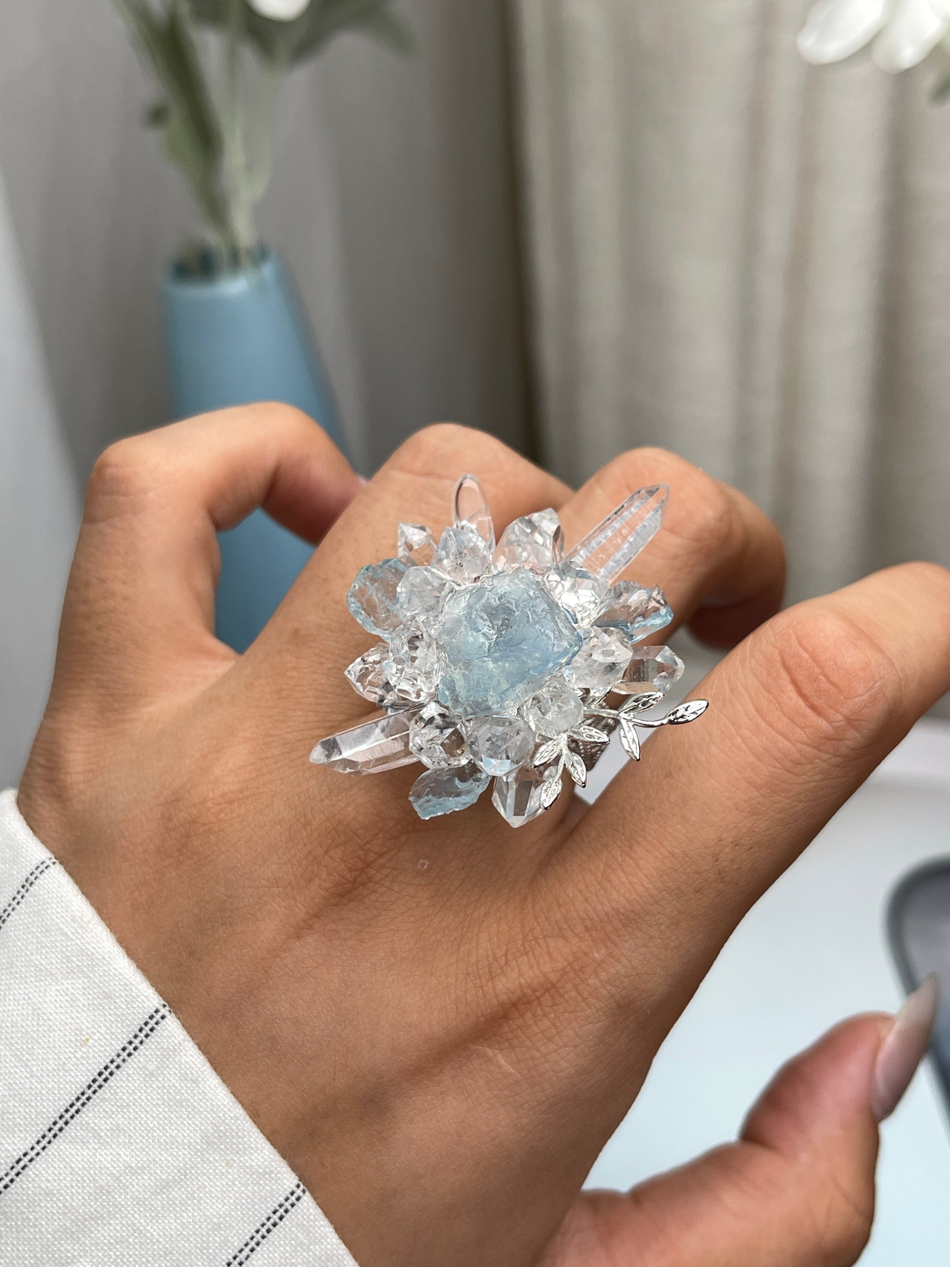 Close up of raw aquamarine Herkimer Diamond Quartz and clear quartz flower ring worn on hand