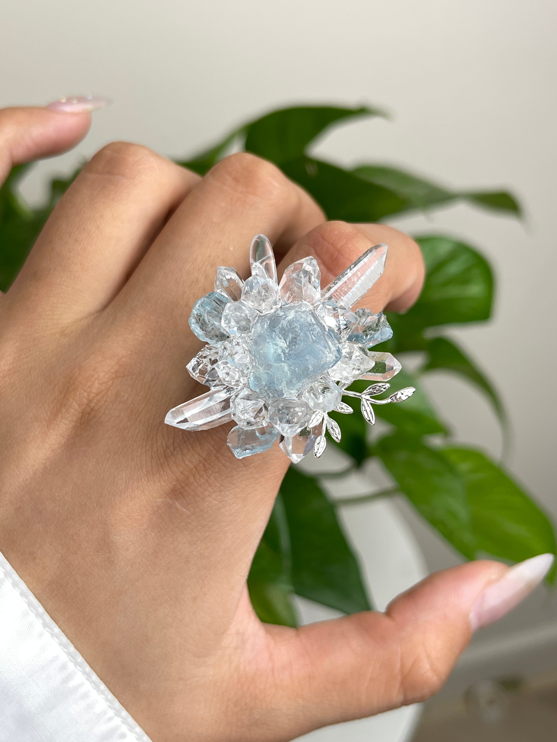 Close up of raw aquamarine Herkimer Diamond Quartz and clear quartz flower ring worn on hand