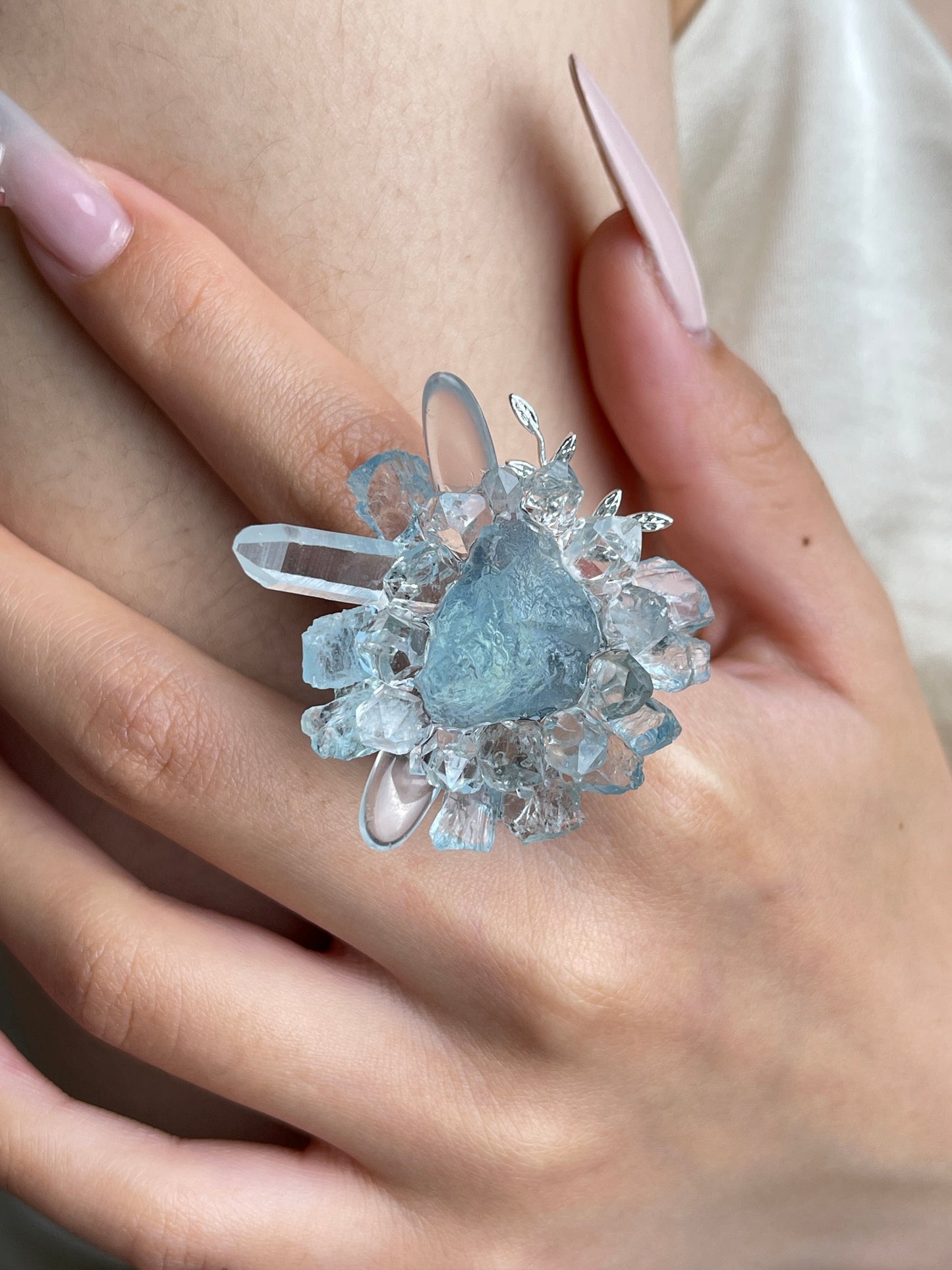 Close up of raw aquamarine Herkimer Diamond Quartz and clear quartz flower ring worn on hand