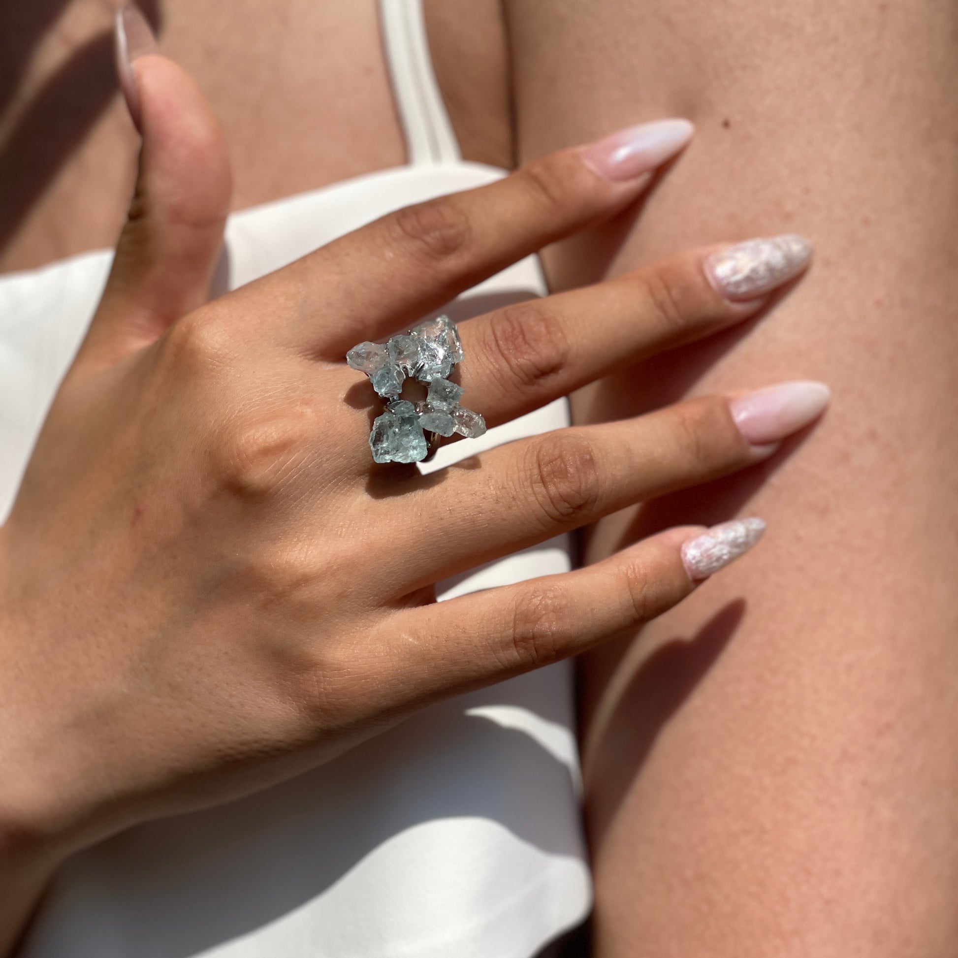 Close-up hand wearing raw Aquamarine and Herkimer Diamond Quartz flower ring