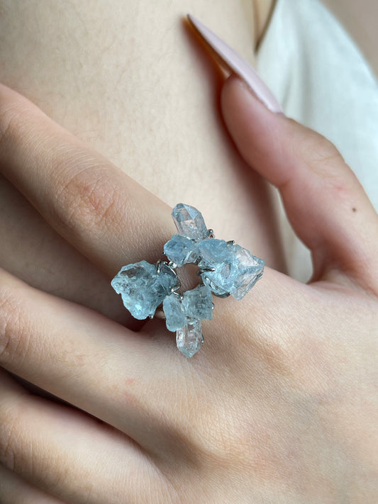 Close-up hand wearing raw Aquamarine and Herkimer Diamond Quartz flower ring