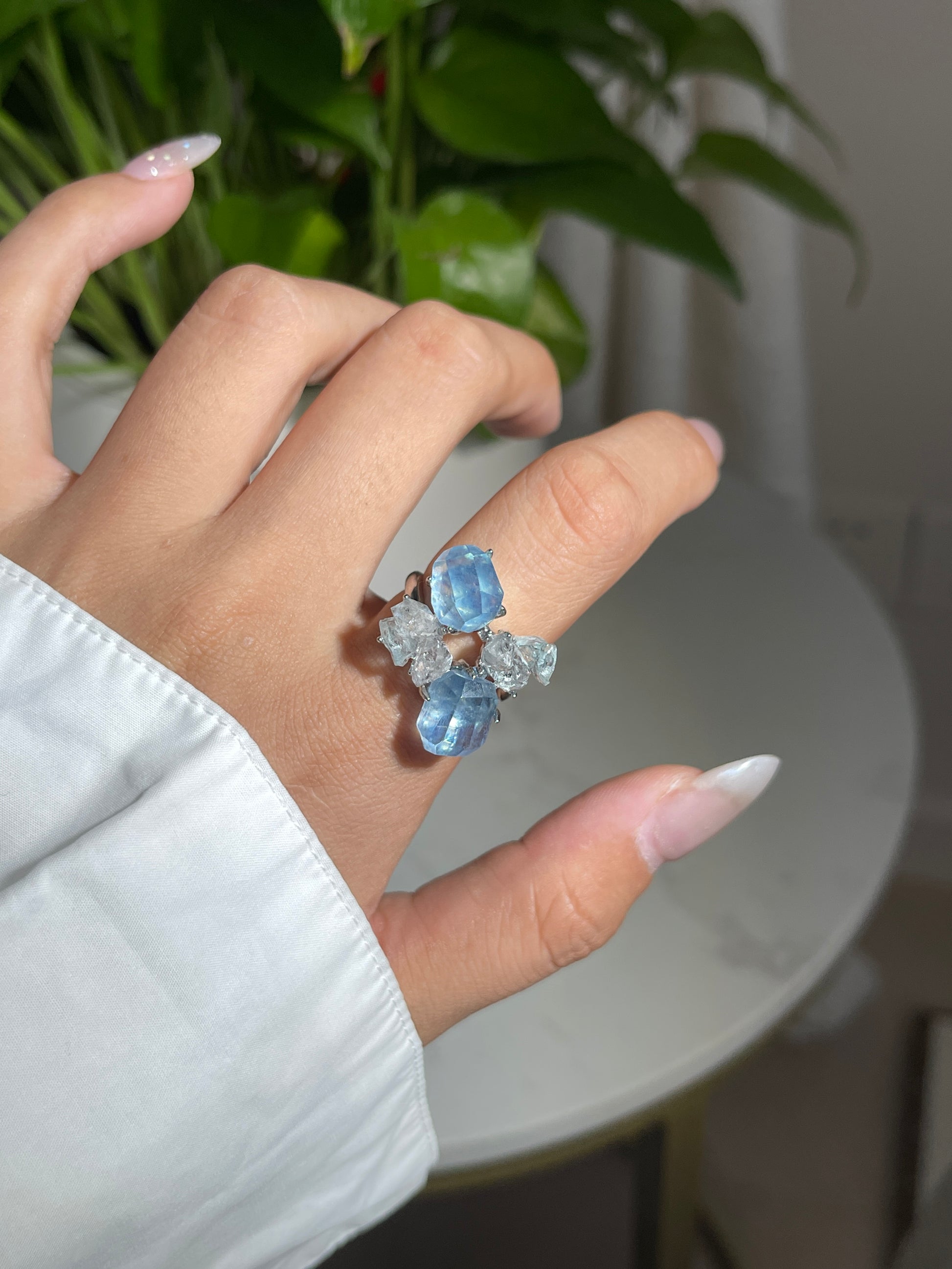 Close-up of aquamarine ring worn on hand with blue topaz and Hakima Diamond quartz natural crystal jewelry