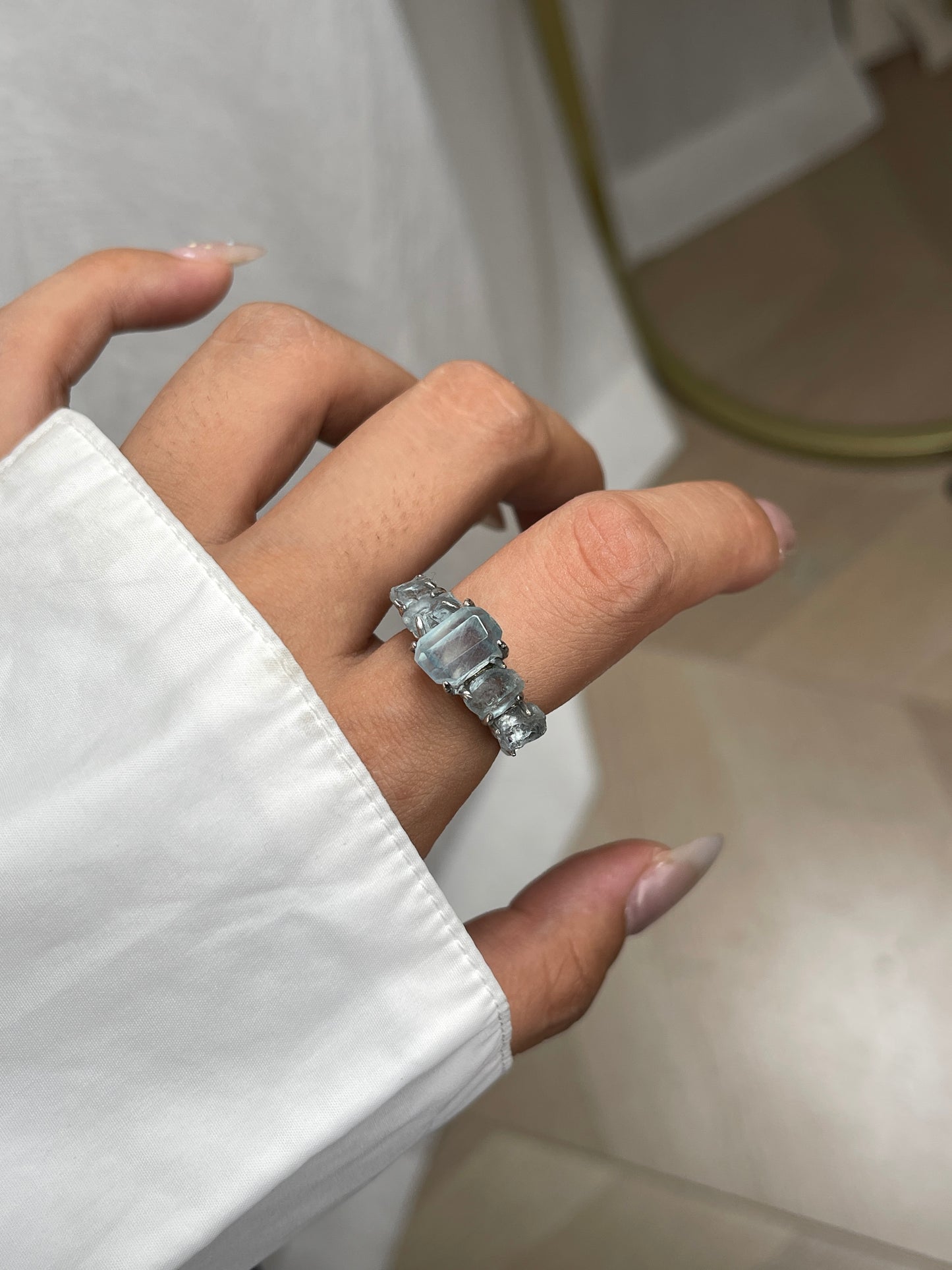 Close up of aquamarine row ring worn on hand with hand cut and raw aquamarine from Brazil