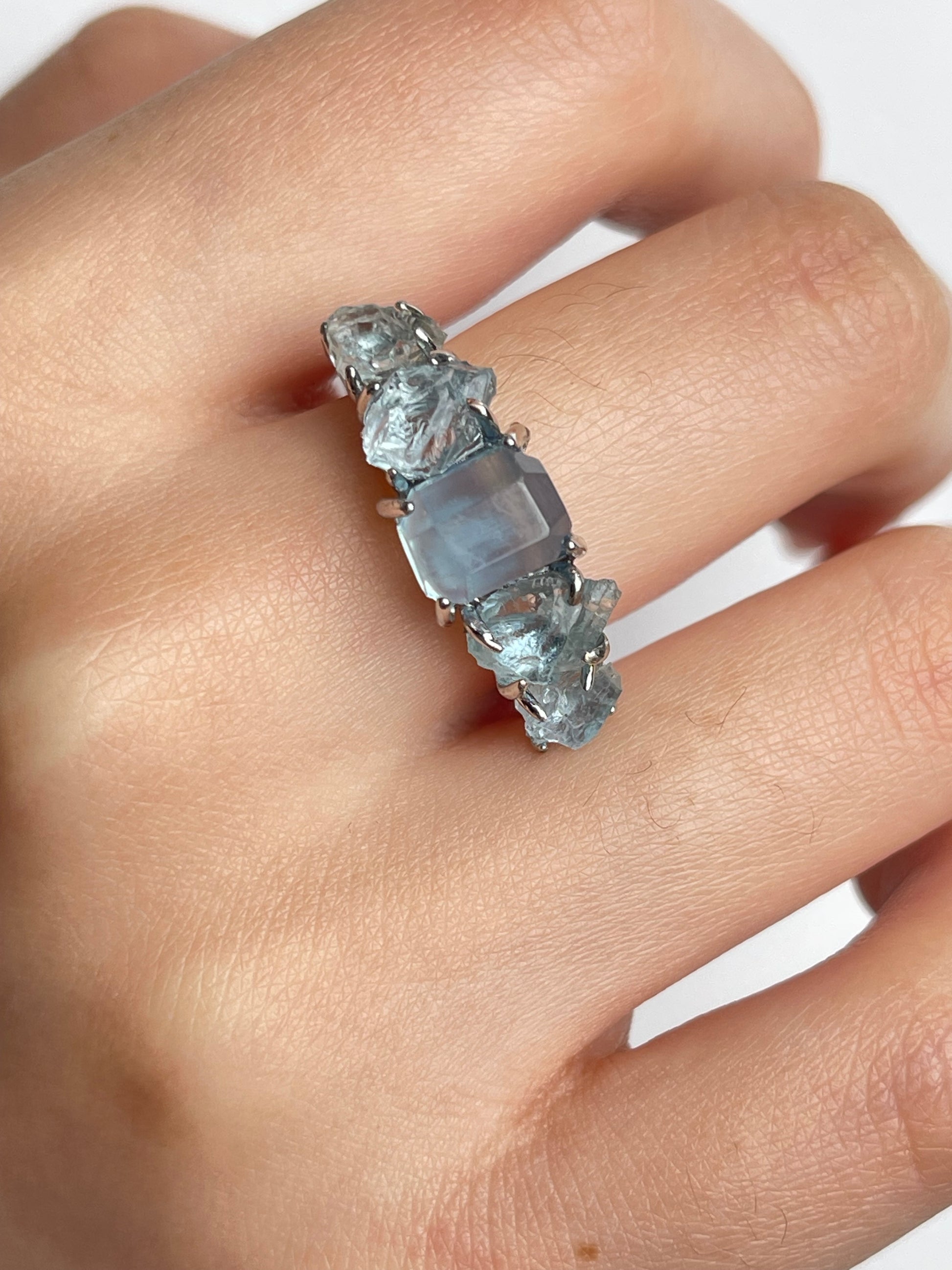 Close up of aquamarine row ring worn on hand with hand cut and raw aquamarine from Brazil