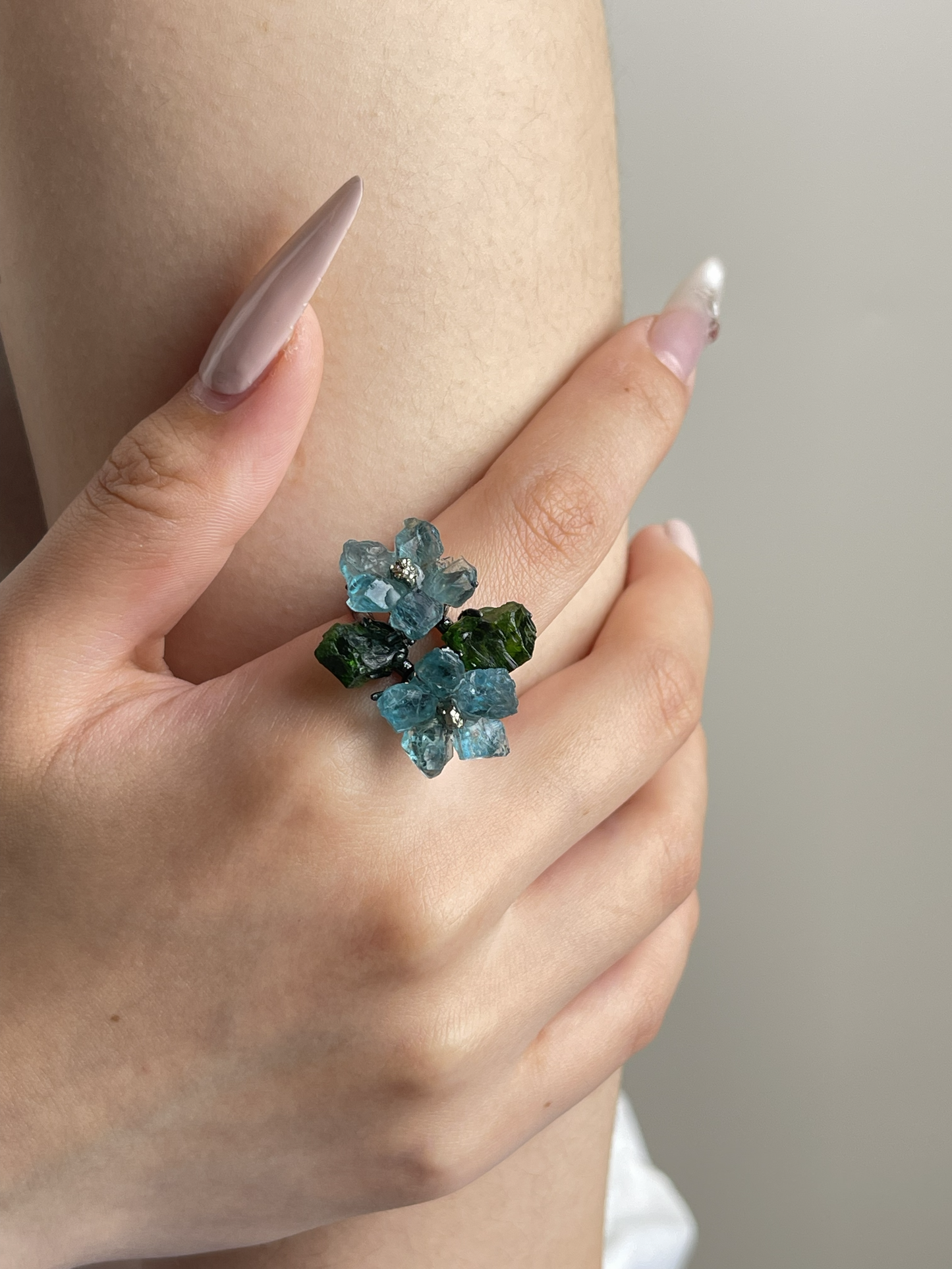 Close-up hand view of Blue Apatite flower ring with Chalcopyrite and Chrome Diopside