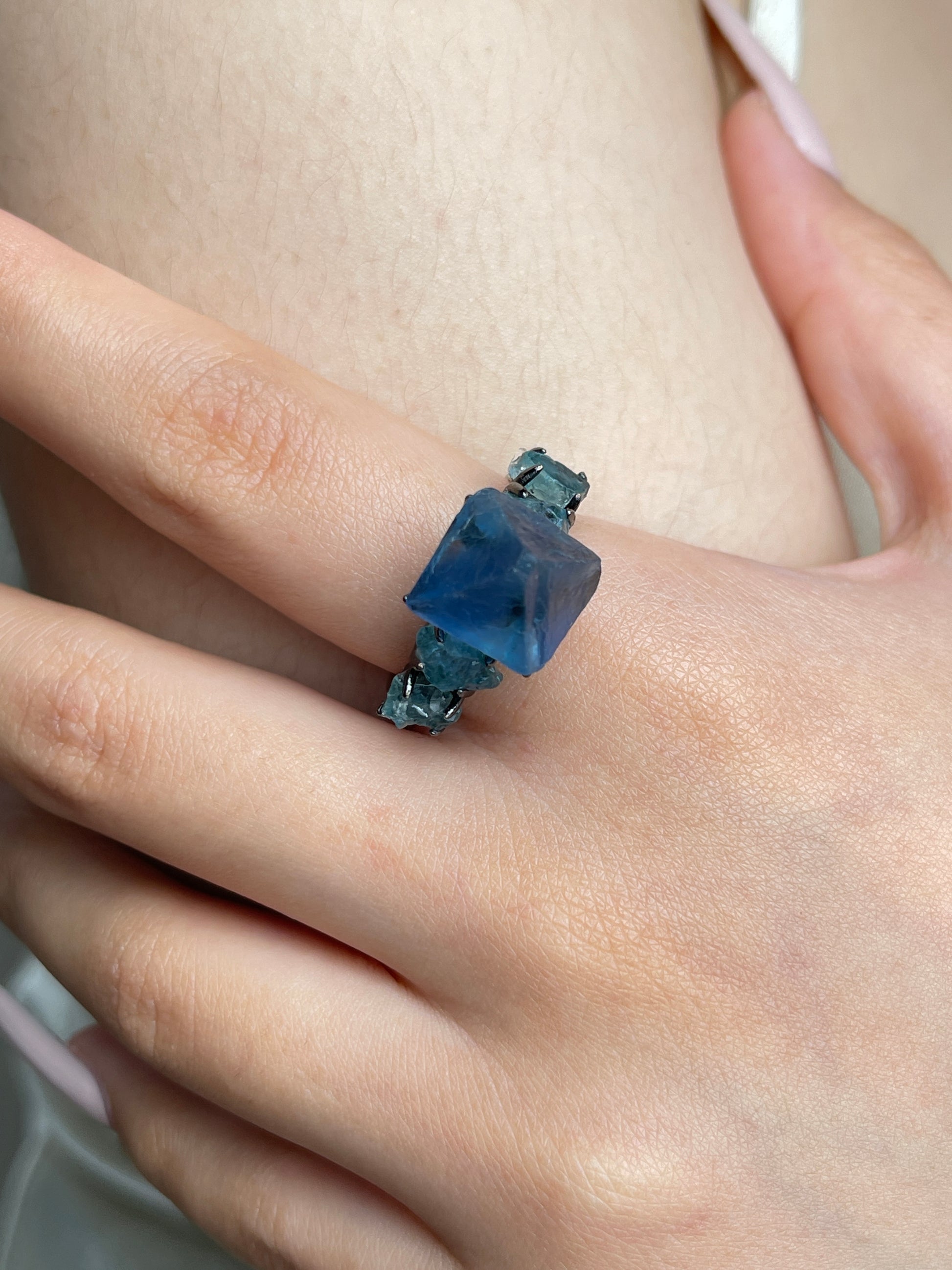 Close up of blue octahedral fluorite and blue apatite ring worn on hand