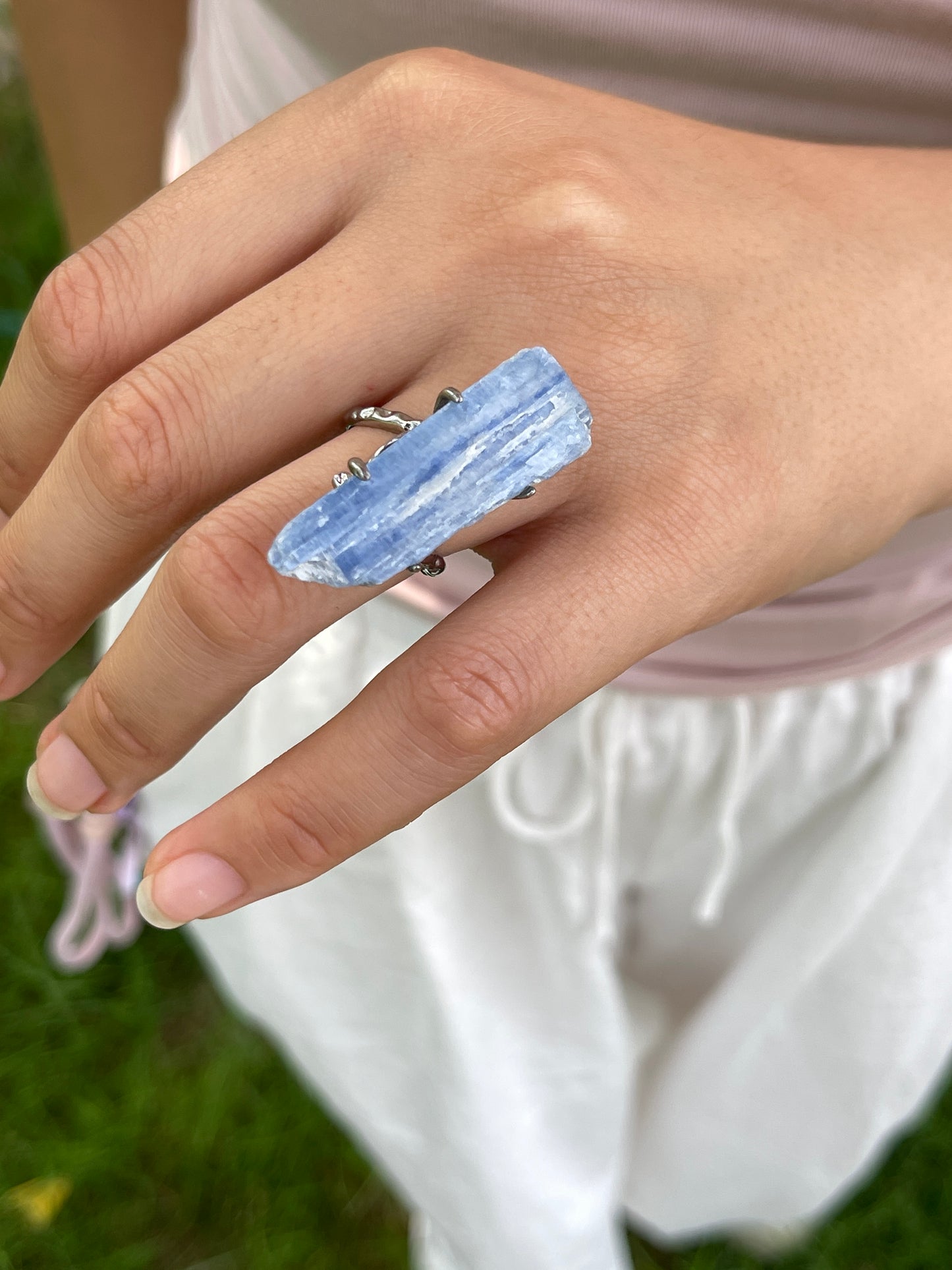 Close-up hand shot of blue kyanite mineral specimen ring showing natural blade-like crystal texture
