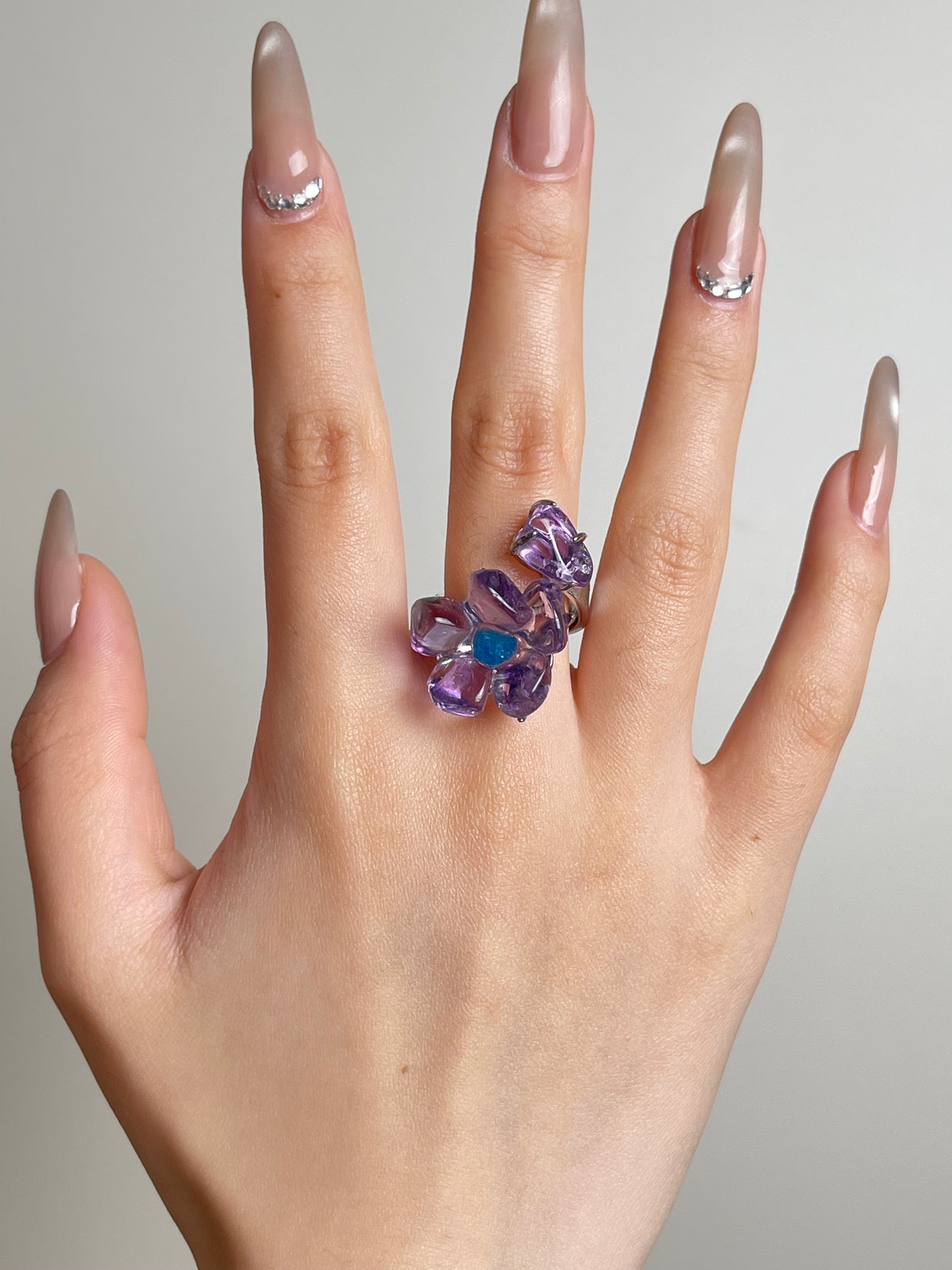 Hand shot of Brazilian amethyst flower ring with blue apatite center