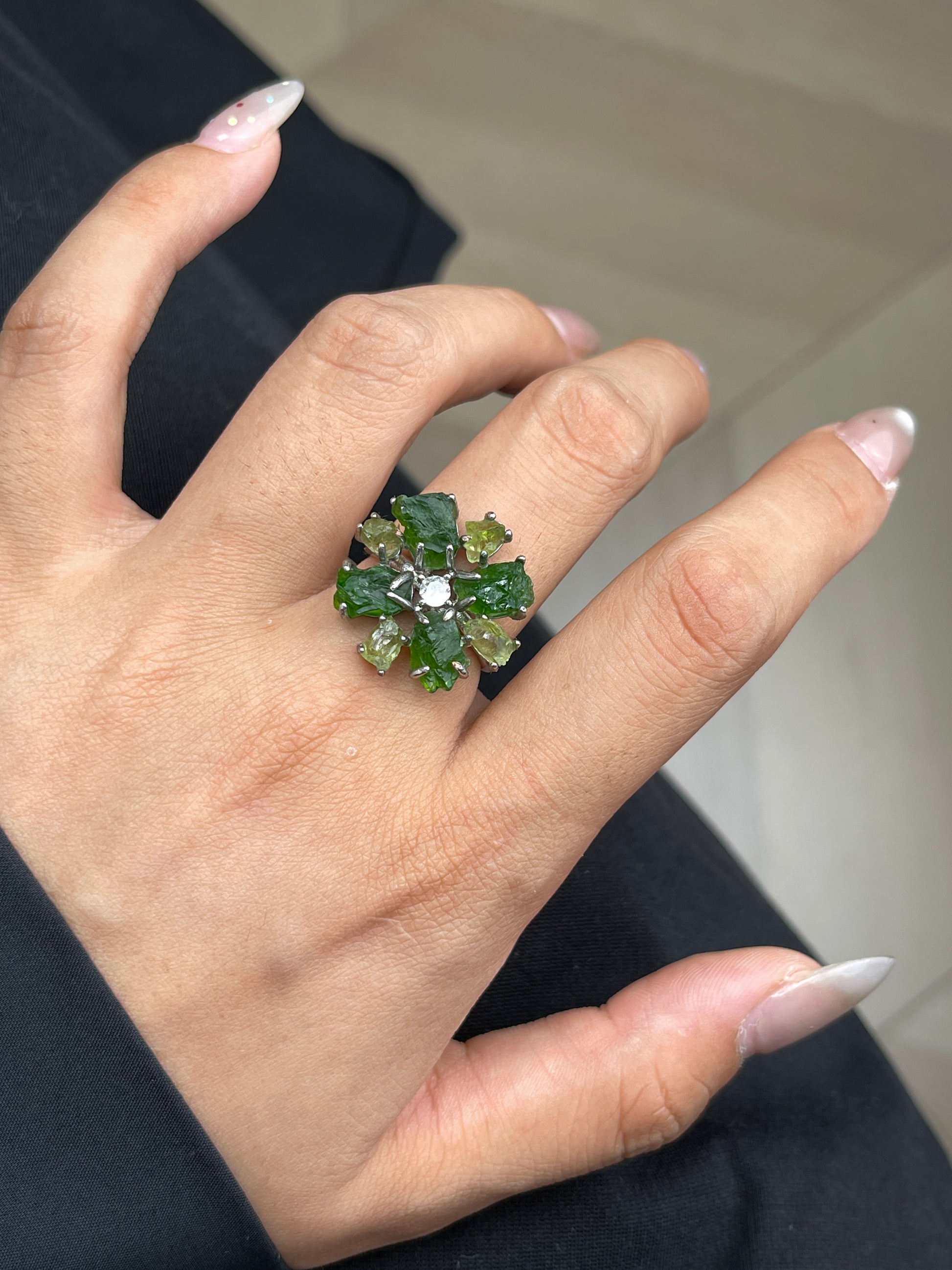 Close-up of Chrome Diopside and Peridot snowflake raw crystal ring worn on hand