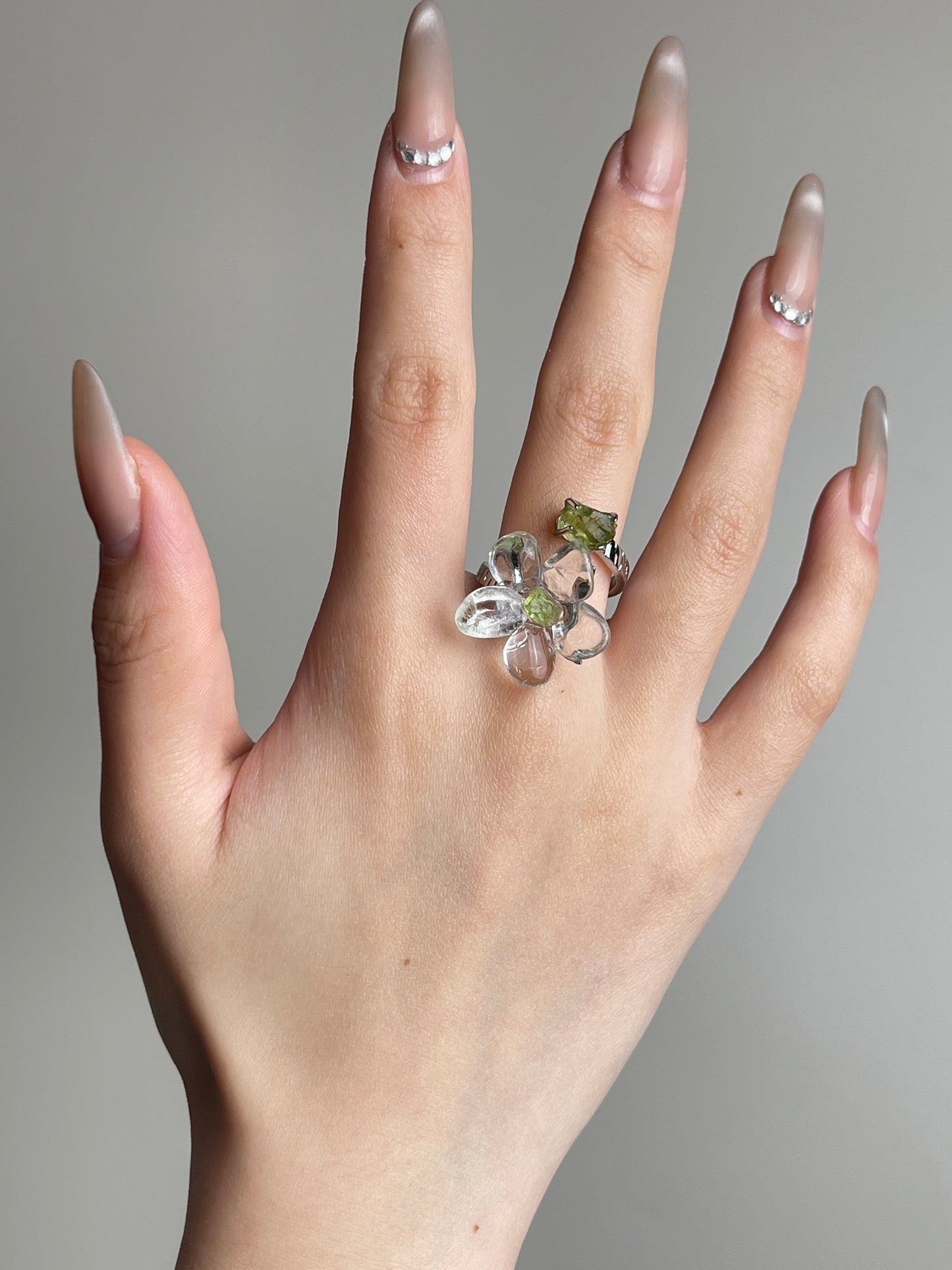 Hand view of Clear Quartz Flower Ring with raw Peridot
