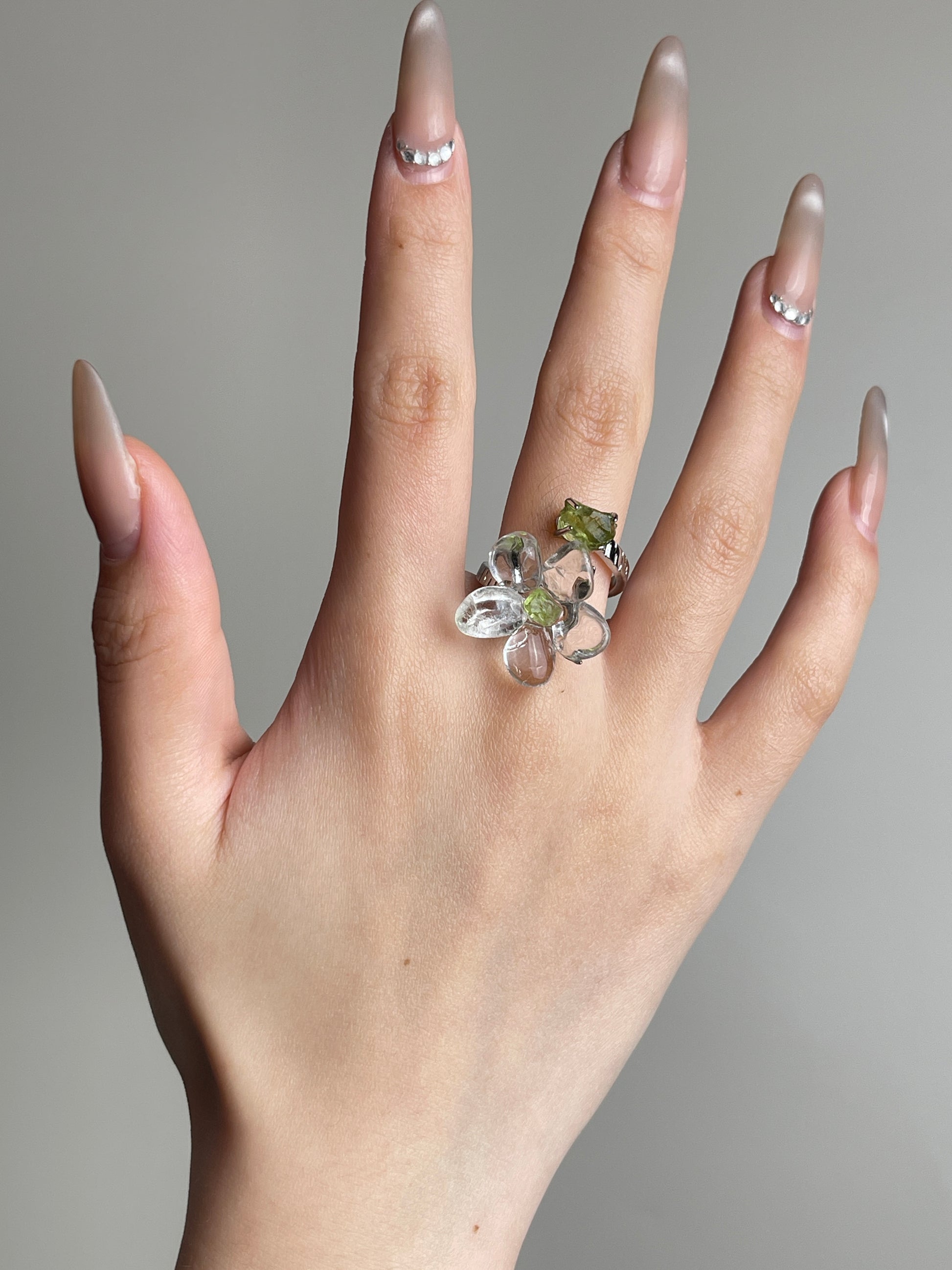 Hand view of Clear Quartz Flower Ring with raw Peridot