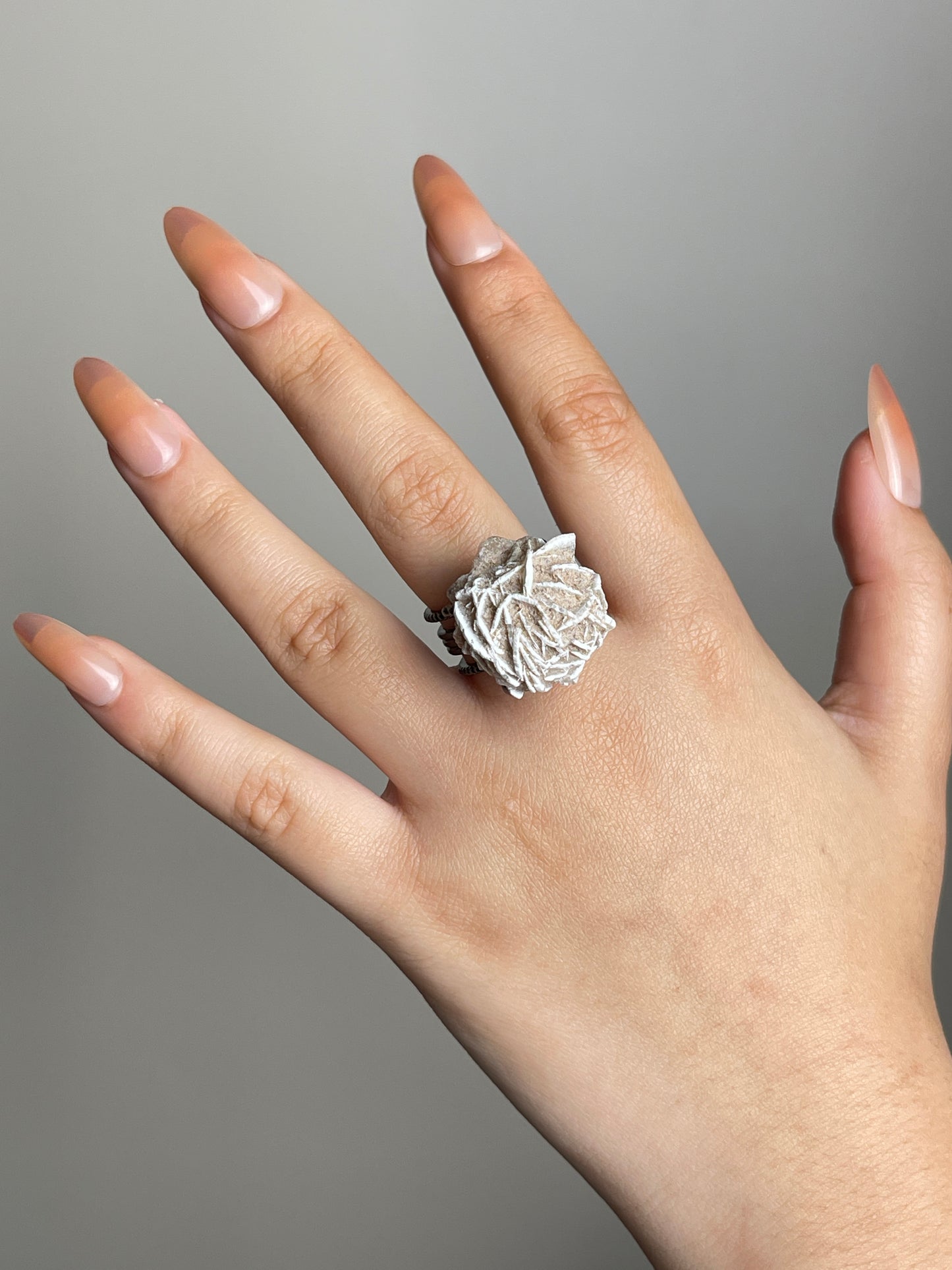 Hand shot of Desert Rose mineral specimen ring from Morocco in natural light.
