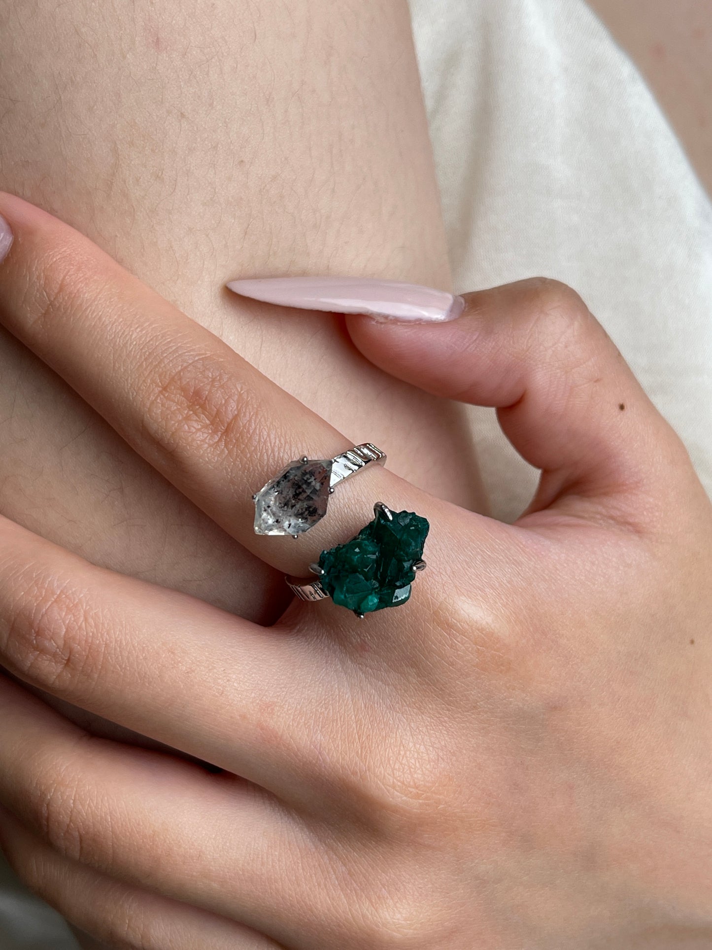 Close up of raw Dioptase and Herkimer Diamond Quartz ring on hand