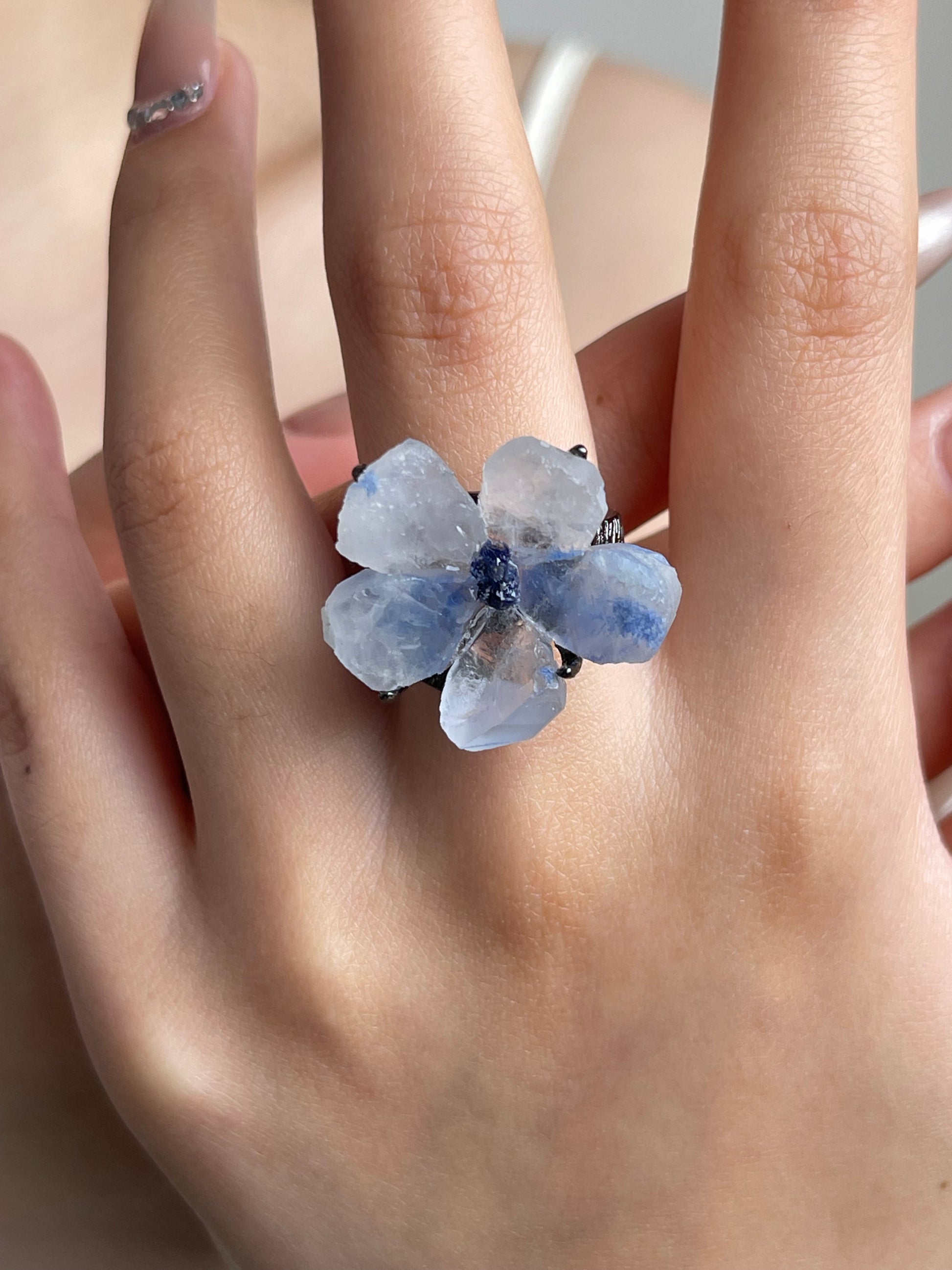 Close-up hand shot of dumortierite quartz flower ring with tanzanite fluorite