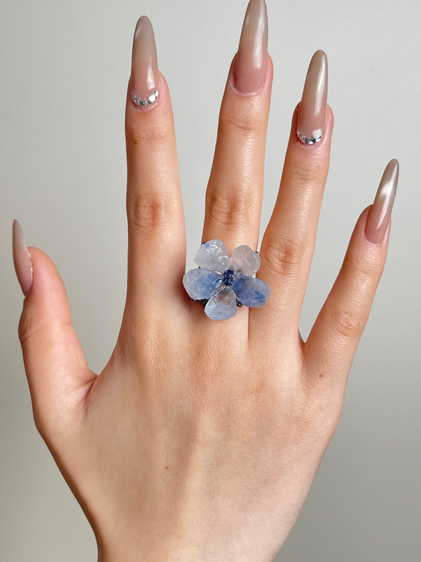 Hand shot of dumortierite quartz flower ring with tanzanite fluorite center