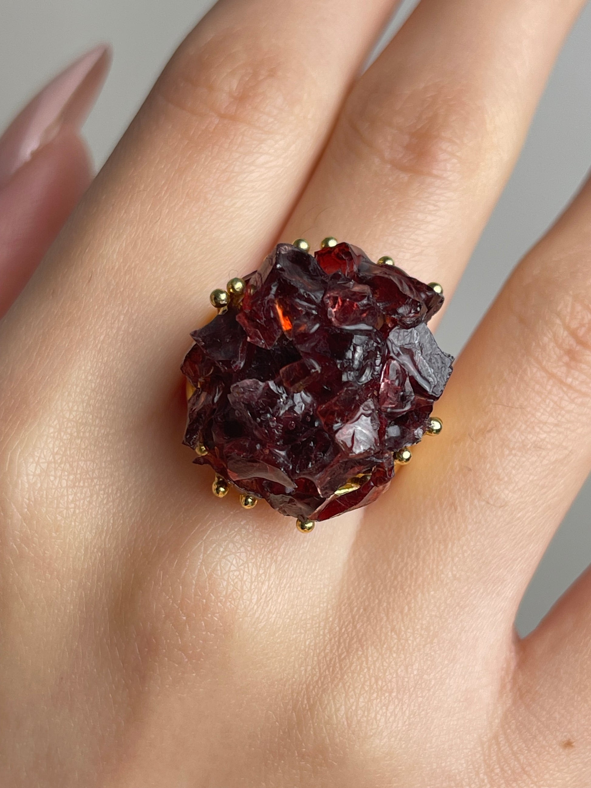Close up of garnet bouquet raw crystal ring worn on hand