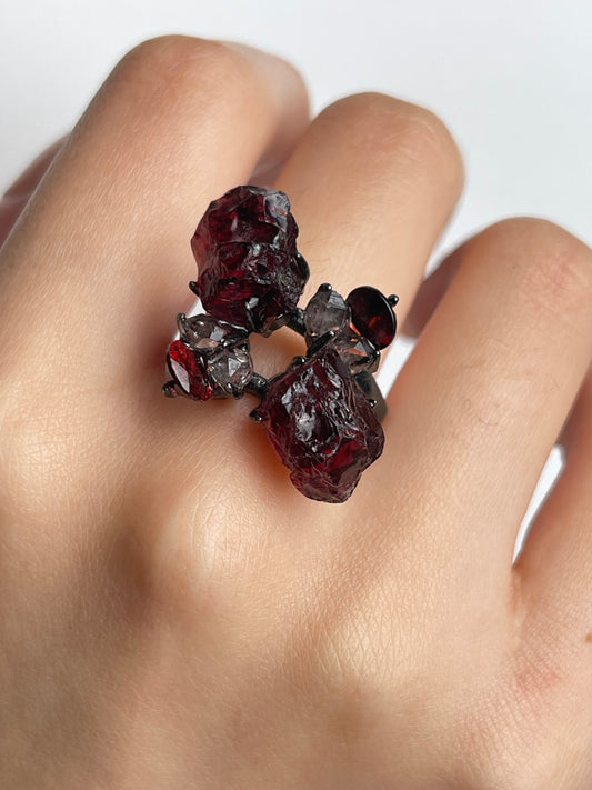 Close up of garnet ring worn on hand with raw garnet cut garnet and Hakima Diamond Quartz