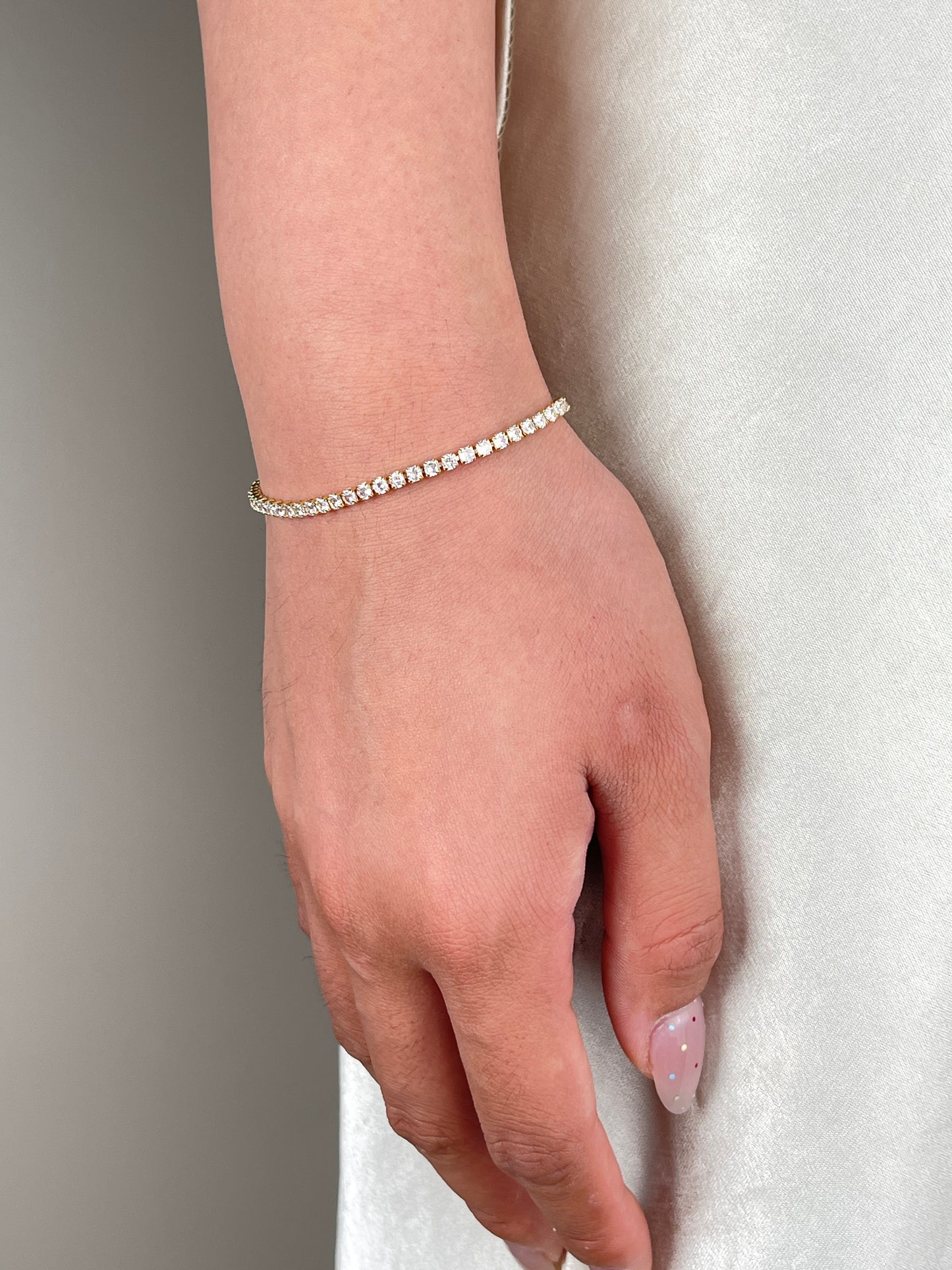 Close-up of a gold-tone cubic zirconia tennis bracelet worn on the wrist