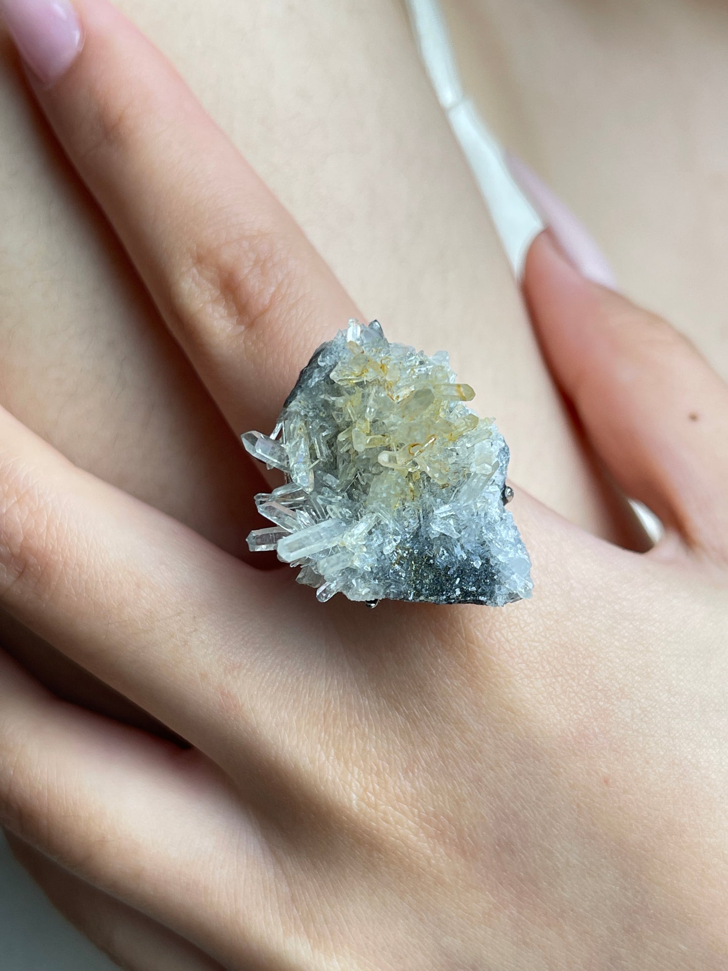 Close-up of needle quartz cluster mineral specimen ring on hand