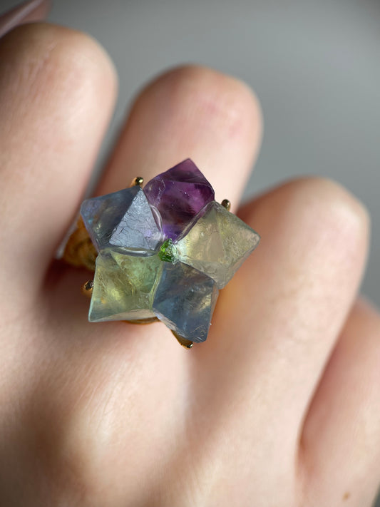 Close-up hand shot of octahedral fluorite flower ring with peridot center showing natural crystal geometry