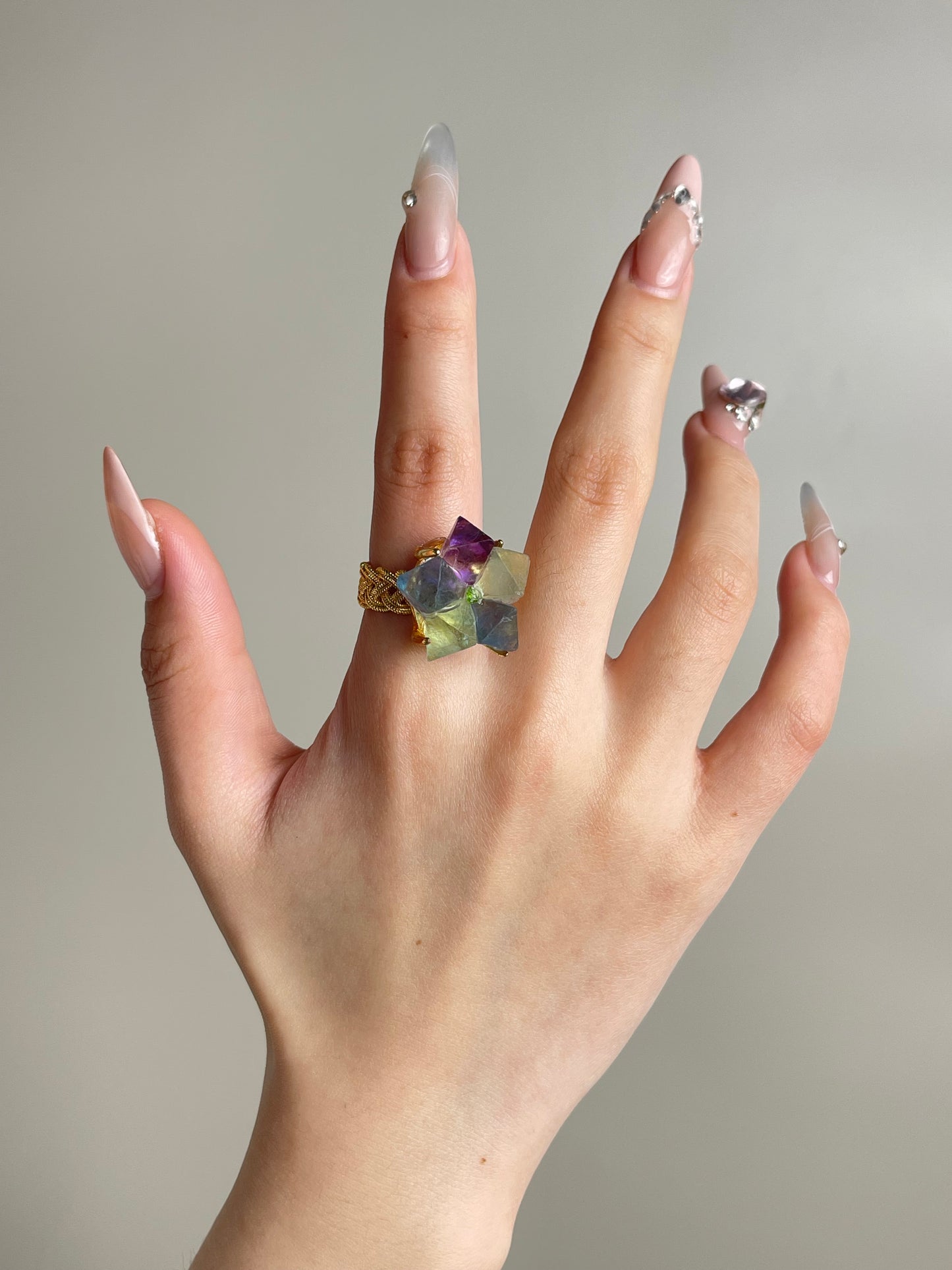 Octahedral fluorite flower ring with peridot center worn on hand in gold finish
