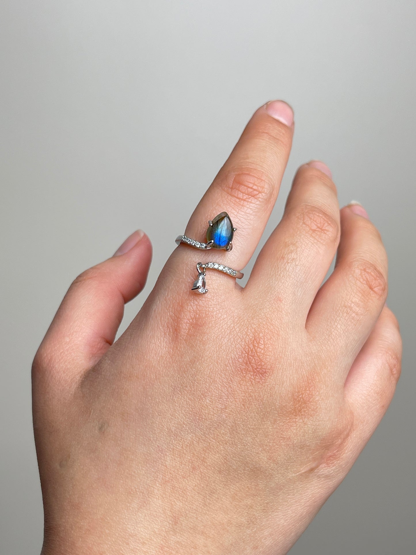 Hand wearing pear cut Labradorite open ring from India with blue iridescent flash