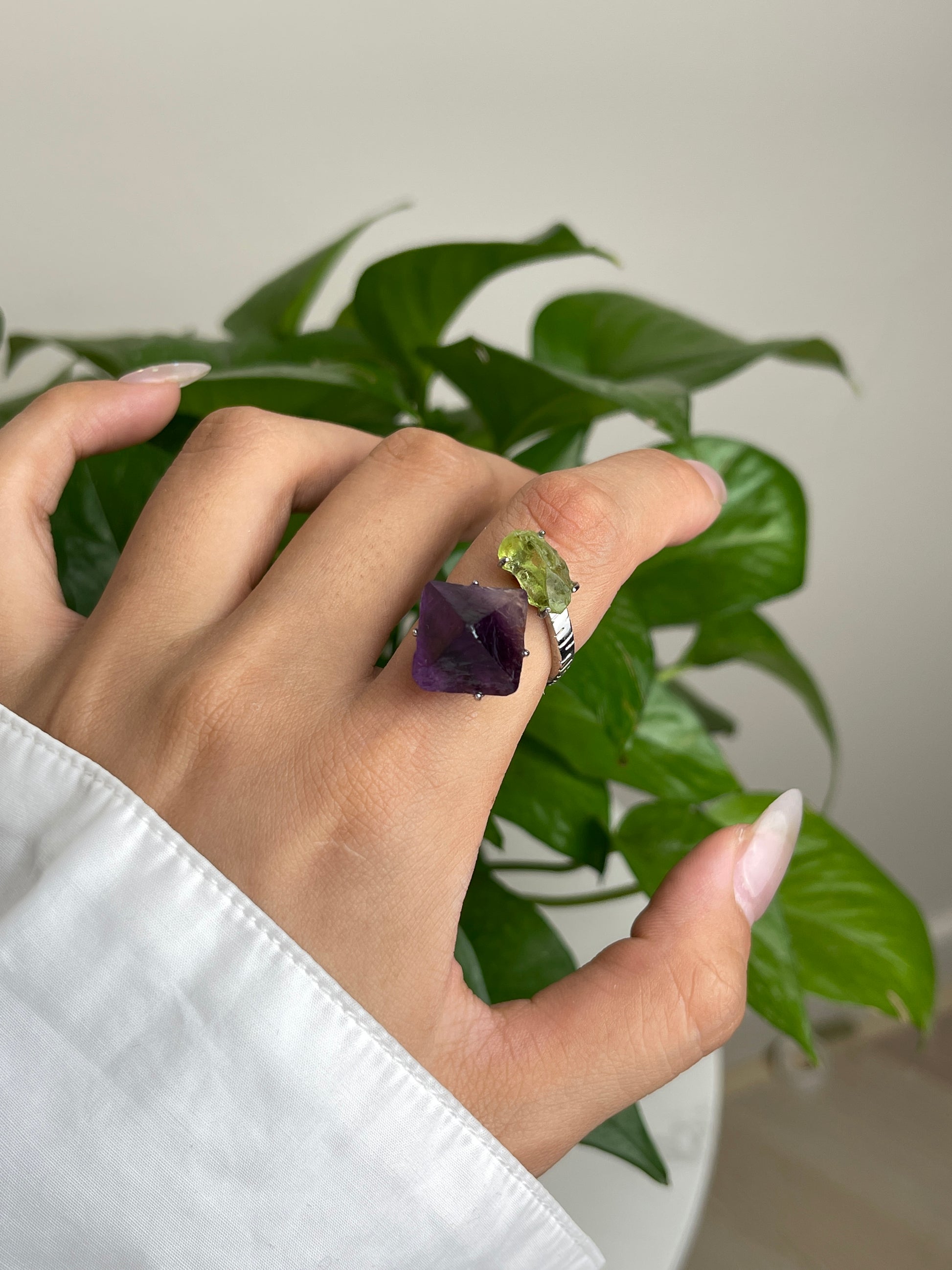 Close up of raw peridot and purple fluorite ring worn on hand