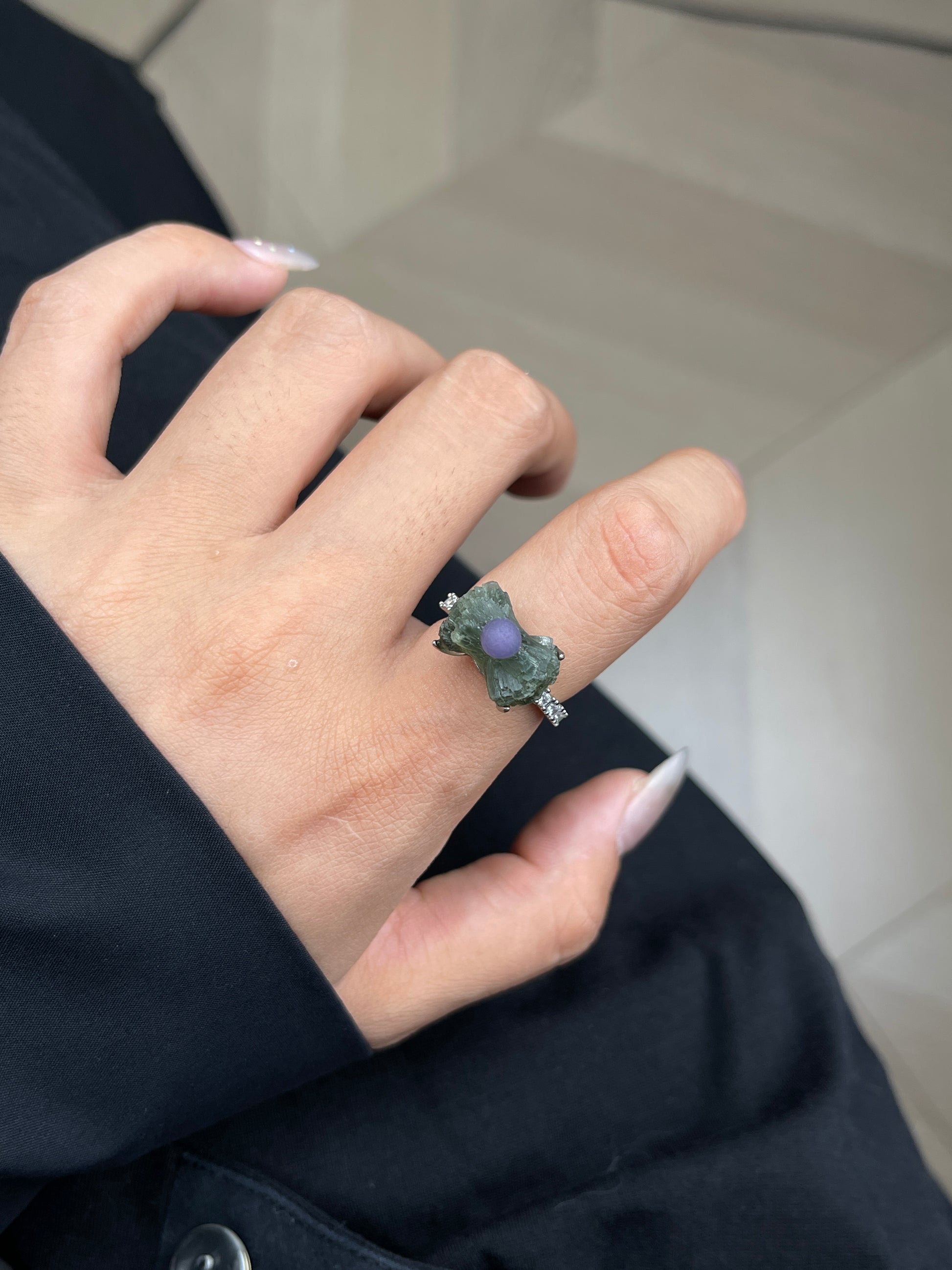 Close up of green prehnite and purple grape agate bow ring worn on hand