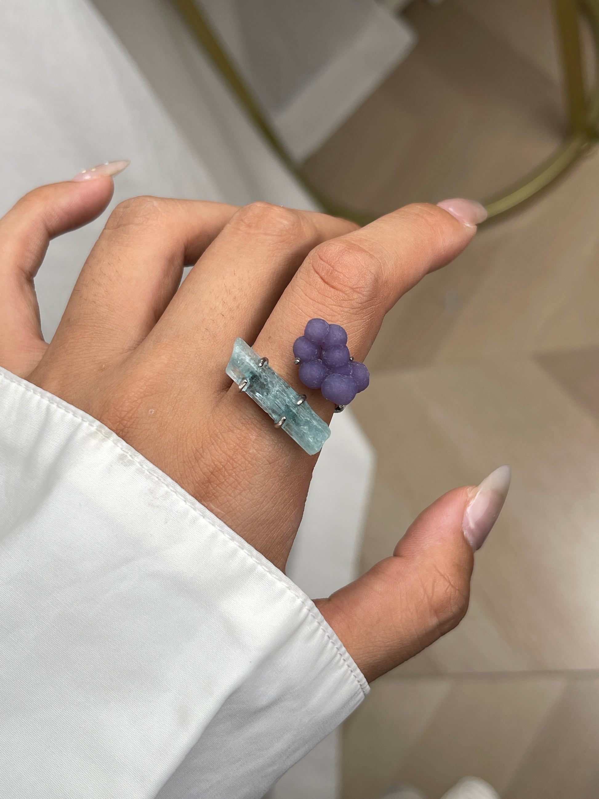 Close-up hand shot of purple grape agate and aquamarine ring showing botryoidal texture and raw blue crystal