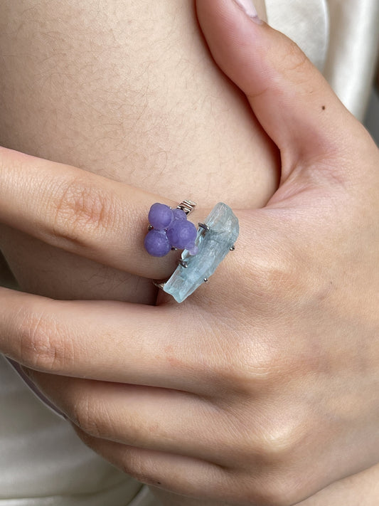 Close-up hand shot of purple grape agate and aquamarine ring showing botryoidal texture and raw blue crystal