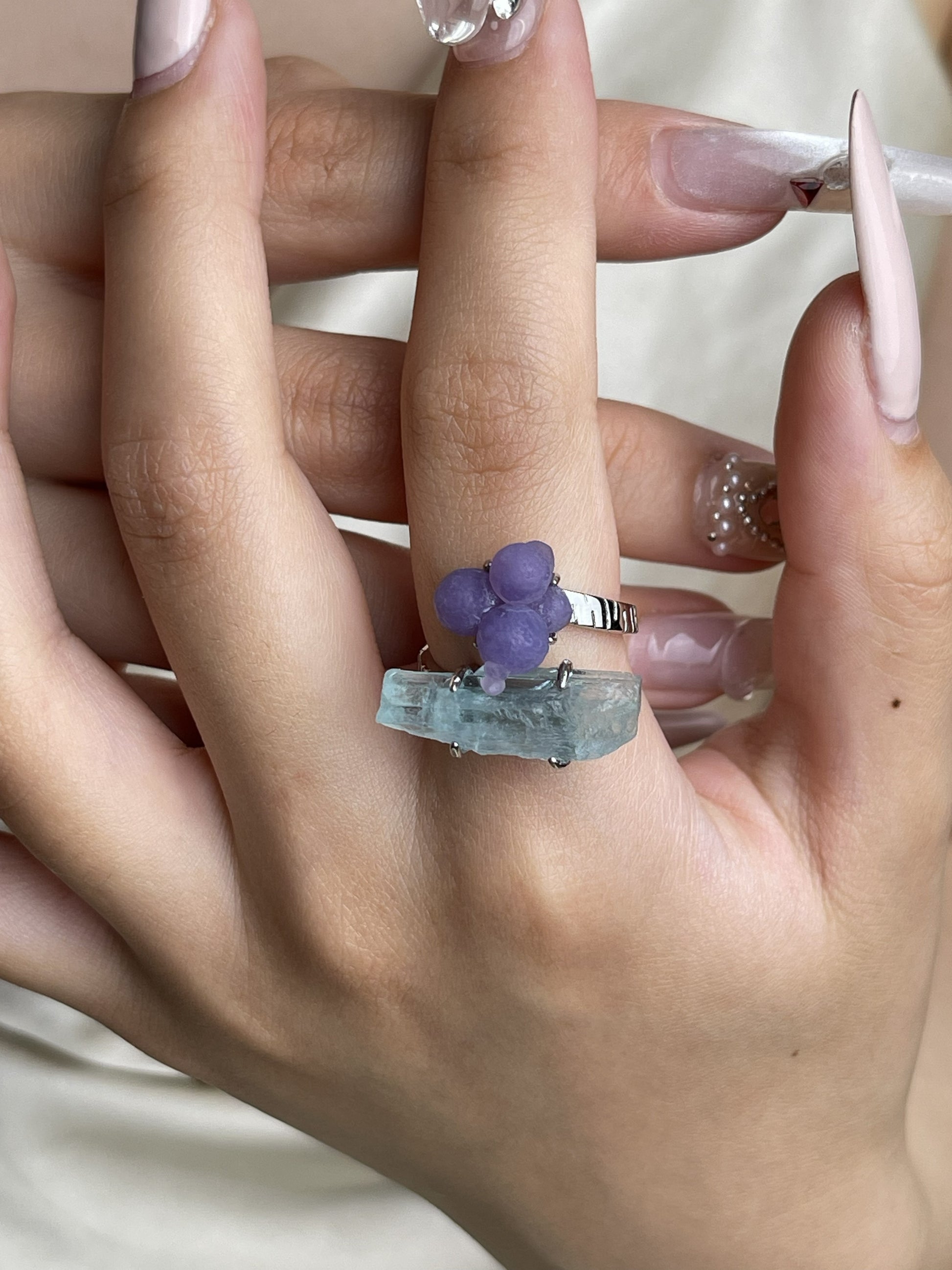 Purple grape agate and aquamarine ring worn on hand with natural purple cluster and blue crystal