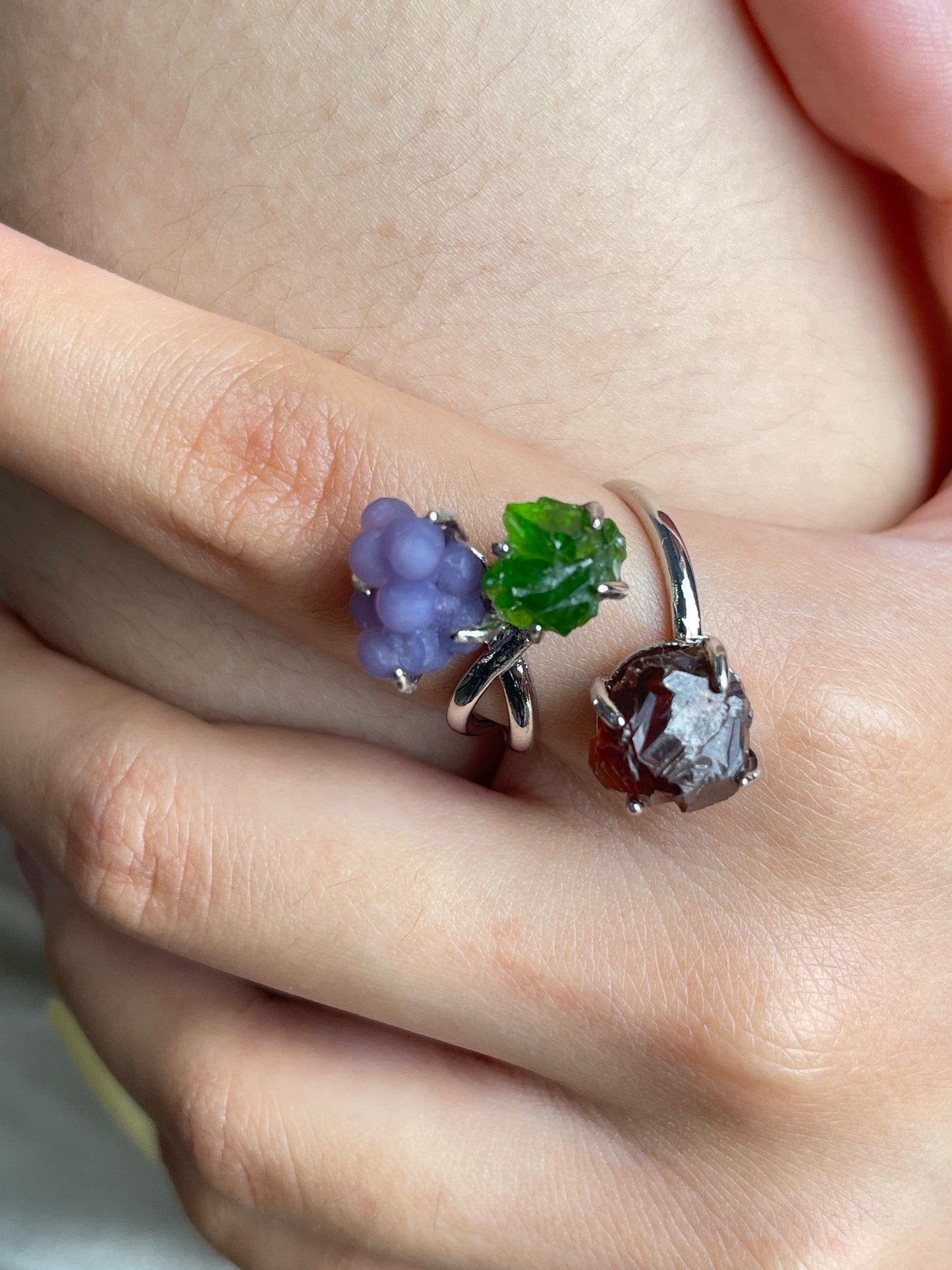 Close up of purple grape agate, chrome diopside and raw garnet ring worn on hand