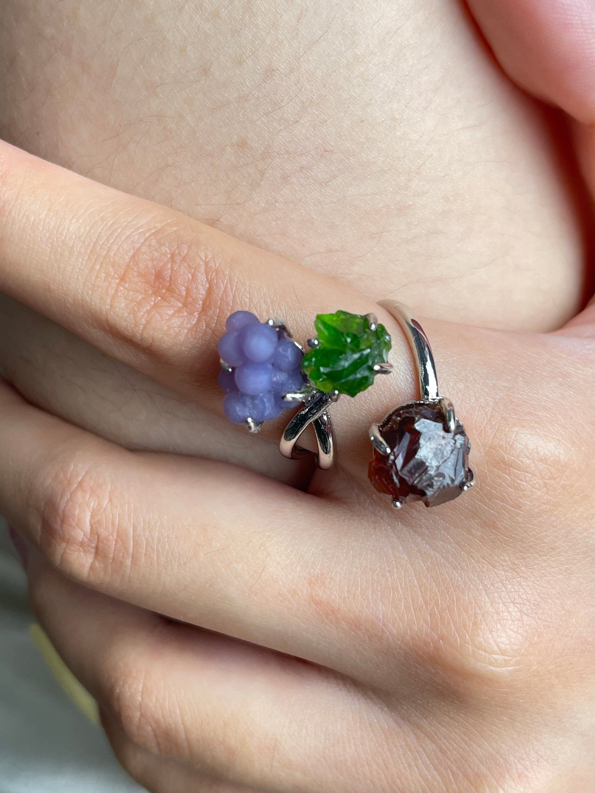Close up of purple grape agate, chrome diopside and raw garnet ring worn on hand
